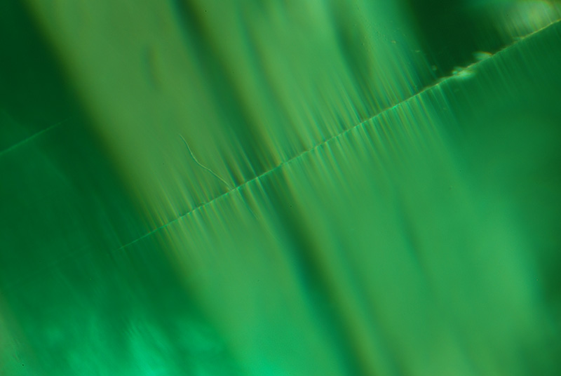 Top: Two-phase thin films seen in both reflected and transmitted light on the basal plane of an emerald from Malysheva, Russia. Below: The same thin films as seen looking parallel to the basal pinacoid. Specimen courtesy of Tsar Emeralds Corp.; photomicrographs © John I. Koivula/microWorld of Gems